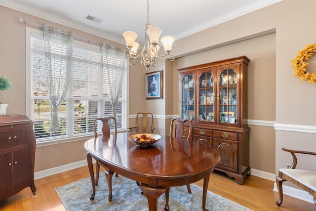 dining area with light wood-style flooring, visible vents, baseboards, and ornamental molding