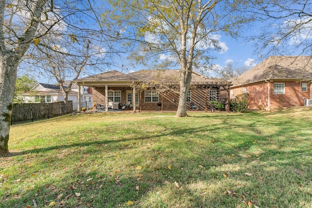 back of house with a yard, brick siding, and fence