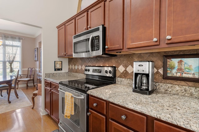 kitchen with tasteful backsplash, light stone counters, stainless steel appliances, crown molding, and light wood-type flooring