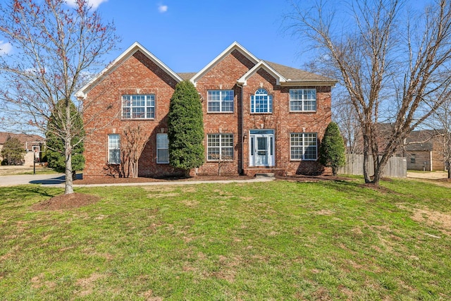 colonial home with brick siding, a front yard, and fence