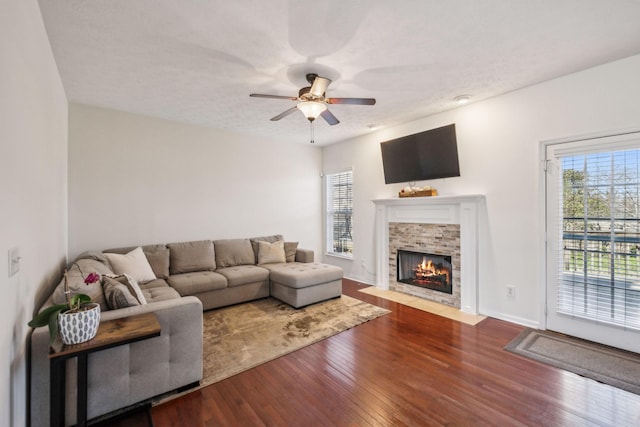 living area featuring hardwood / wood-style floors, ceiling fan, a healthy amount of sunlight, and a fireplace