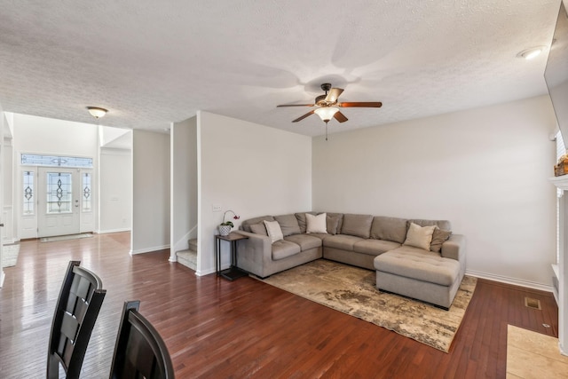 living area with a textured ceiling, wood finished floors, and stairs