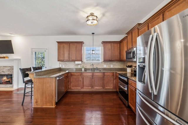 kitchen featuring a breakfast bar, a peninsula, a sink, appliances with stainless steel finishes, and brown cabinets