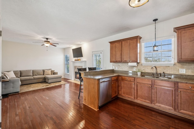 kitchen with open floor plan, dishwasher, a kitchen bar, a peninsula, and a sink