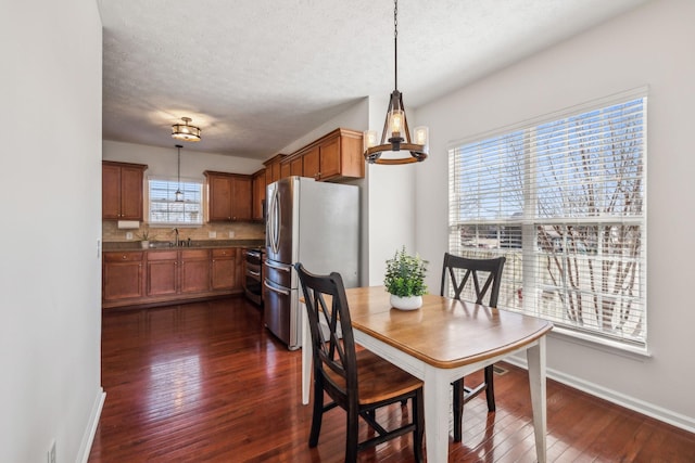 dining space with baseboards, dark wood-type flooring, a chandelier, and a textured ceiling