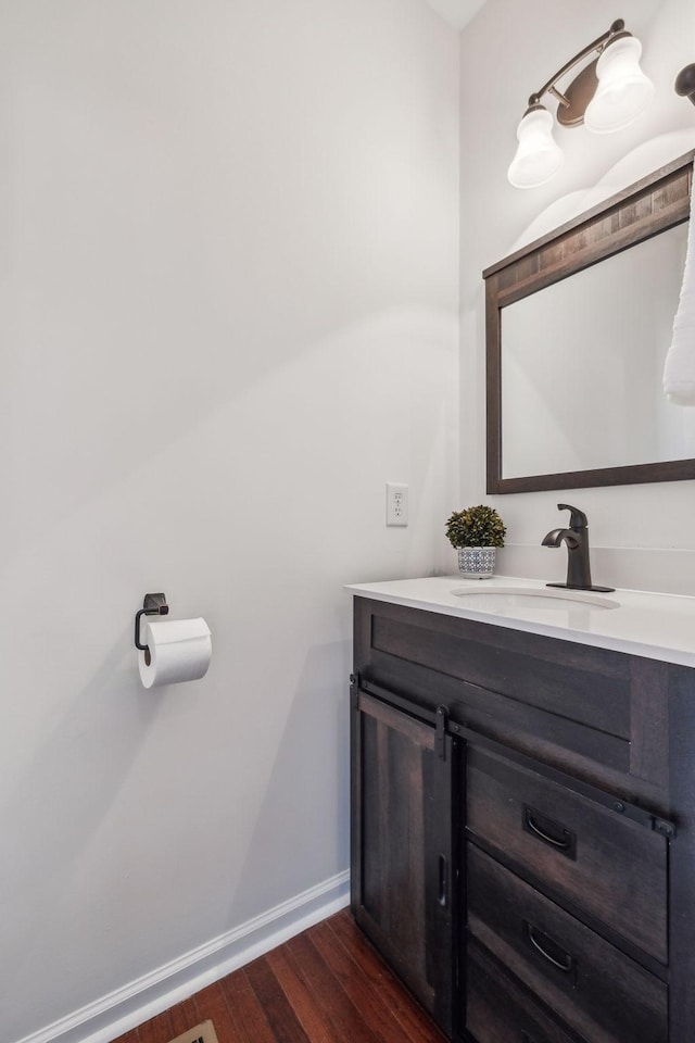 bathroom with baseboards, wood finished floors, and vanity