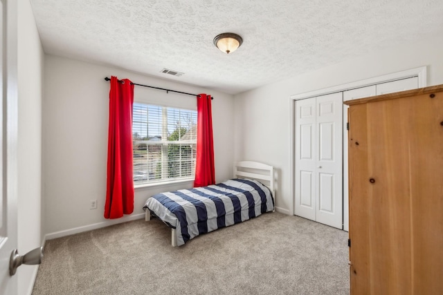 bedroom with visible vents, carpet floors, a textured ceiling, and baseboards