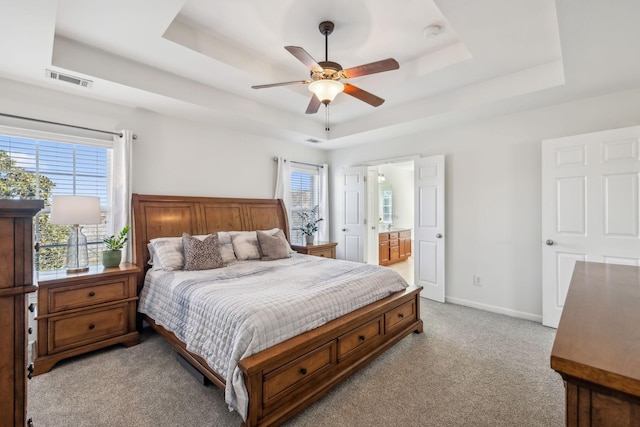 bedroom with multiple windows, light colored carpet, a raised ceiling, and baseboards