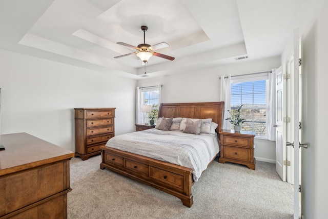 bedroom with baseboards, a raised ceiling, light carpet, and a ceiling fan