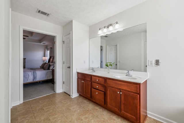 ensuite bathroom featuring a sink, a textured ceiling, ensuite bath, and double vanity