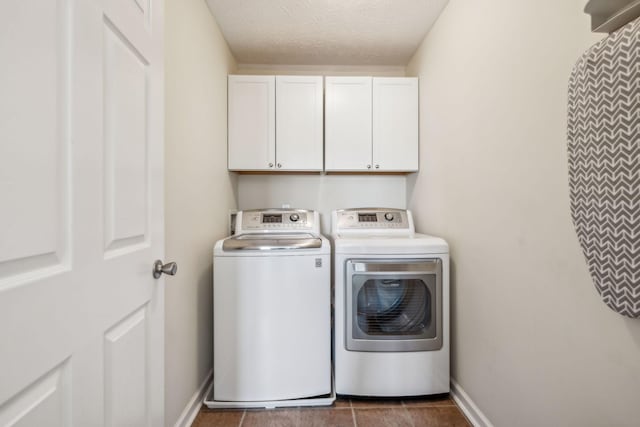 laundry area featuring baseboards, cabinet space, tile patterned flooring, a textured ceiling, and washer and dryer