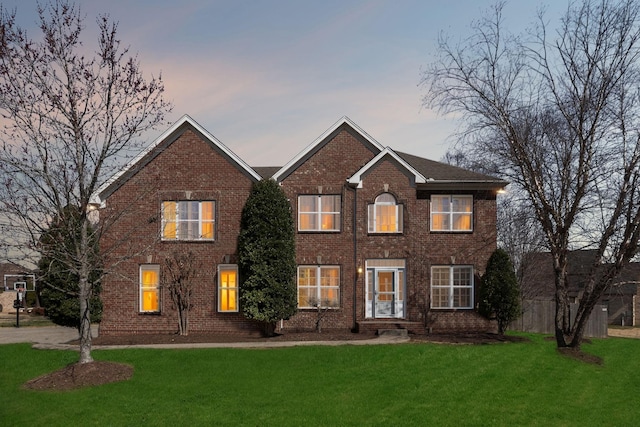 colonial house featuring brick siding and a front yard