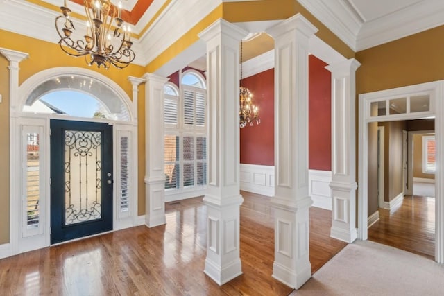 entryway with wood finished floors, decorative columns, and crown molding