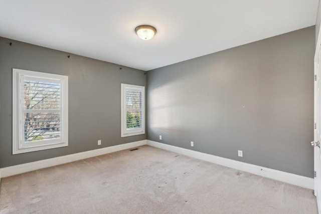 spare room with light carpet, visible vents, and baseboards