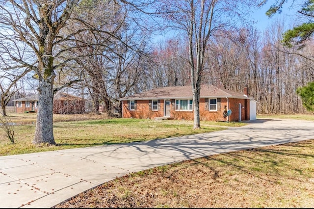 single story home with driveway, brick siding, a chimney, and a front yard