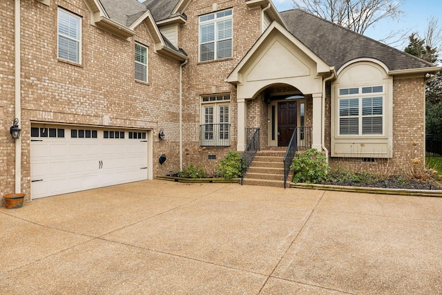 view of front of house with driveway, roof with shingles, crawl space, an attached garage, and brick siding