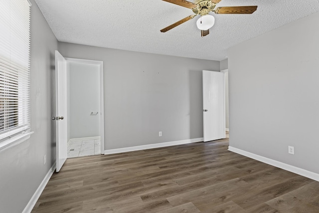 spare room featuring a textured ceiling, ceiling fan, wood finished floors, and baseboards