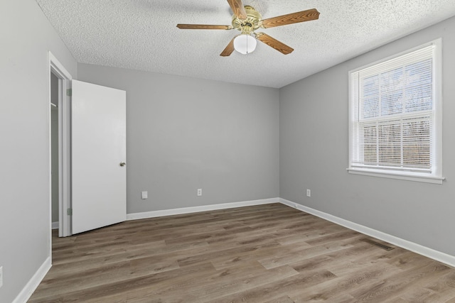 spare room with a textured ceiling, wood finished floors, visible vents, and baseboards