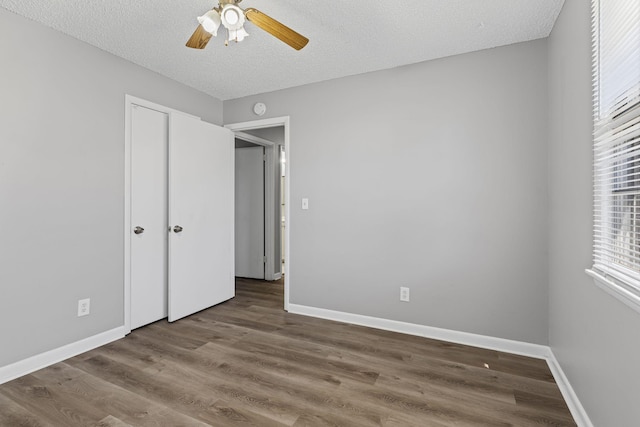 unfurnished bedroom with a textured ceiling, wood finished floors, a ceiling fan, and baseboards