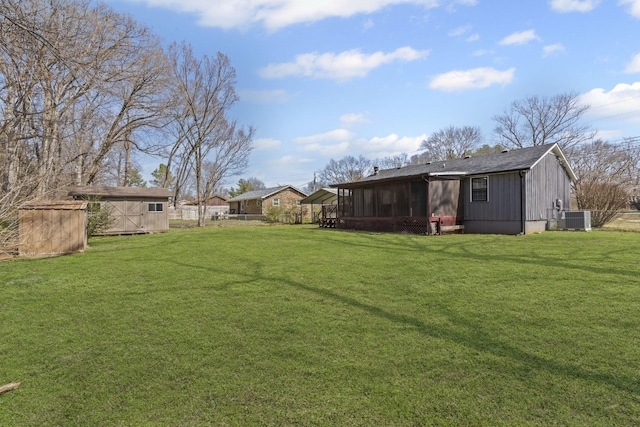 view of yard with central AC unit, a sunroom, an outbuilding, fence, and a shed