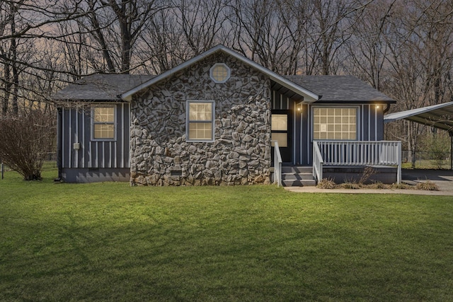 ranch-style house with roof with shingles, a front yard, crawl space, a carport, and stone siding