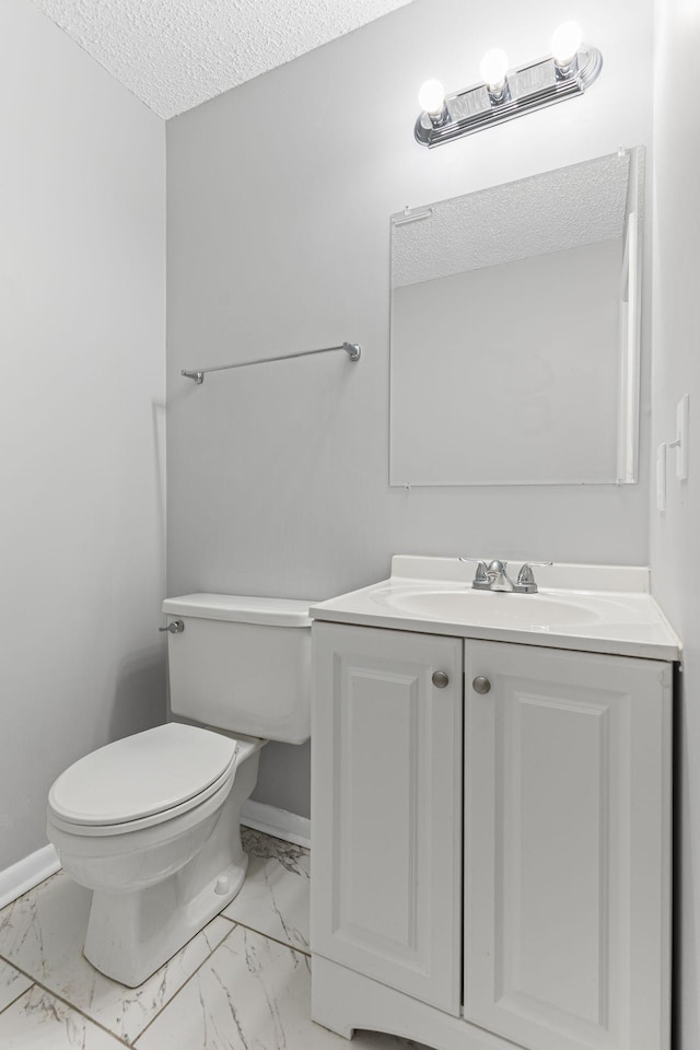 bathroom with marble finish floor, baseboards, a textured ceiling, and toilet