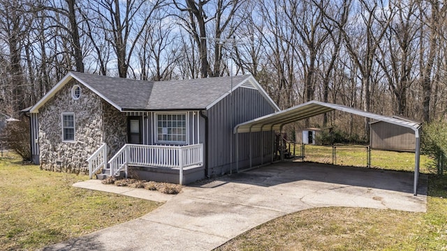 view of front of home with a shingled roof, covered porch, a carport, driveway, and a front lawn