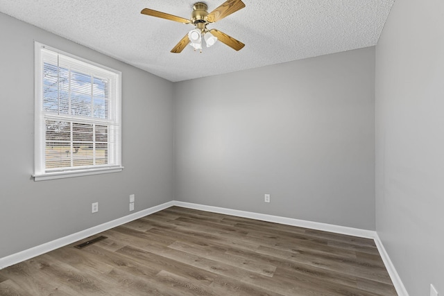 spare room featuring visible vents, a ceiling fan, a textured ceiling, wood finished floors, and baseboards