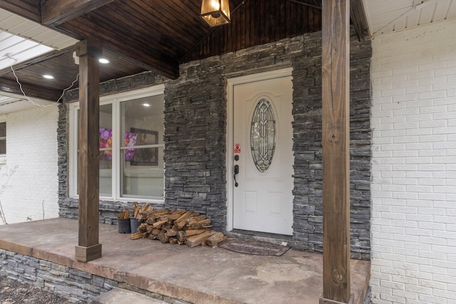 entrance to property with a porch and brick siding