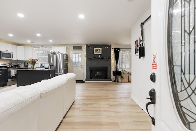 living area featuring recessed lighting, a fireplace, and light wood finished floors