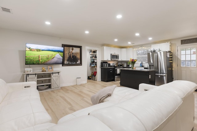 living area featuring light wood-style flooring, visible vents, and recessed lighting