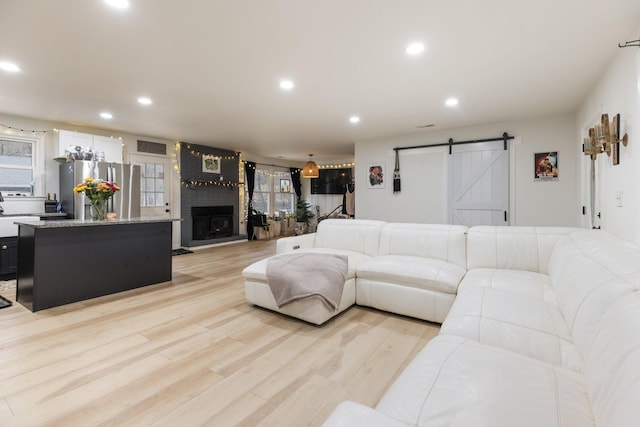 living area with a barn door, light wood-style flooring, and recessed lighting