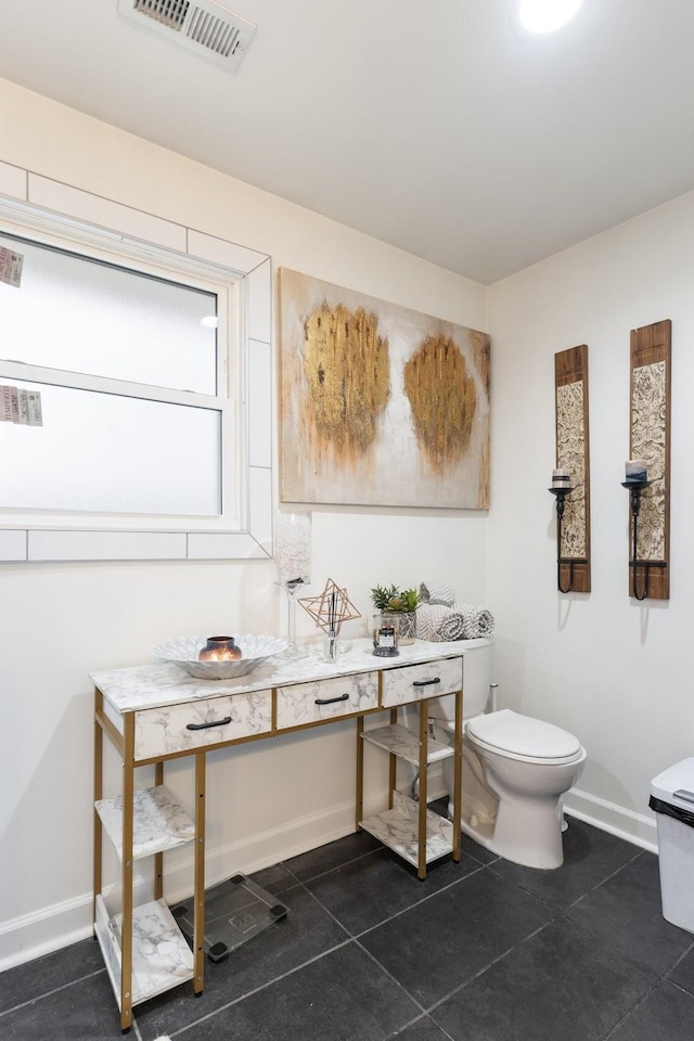 bathroom featuring toilet, tile patterned flooring, visible vents, and baseboards