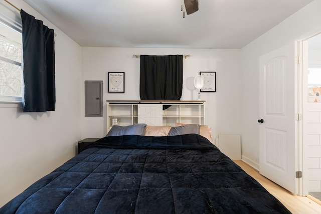 bedroom with ceiling fan, wood finished floors, and electric panel