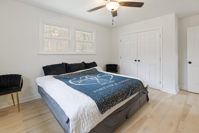 bedroom with light wood-style flooring, baseboards, ceiling fan, and a closet