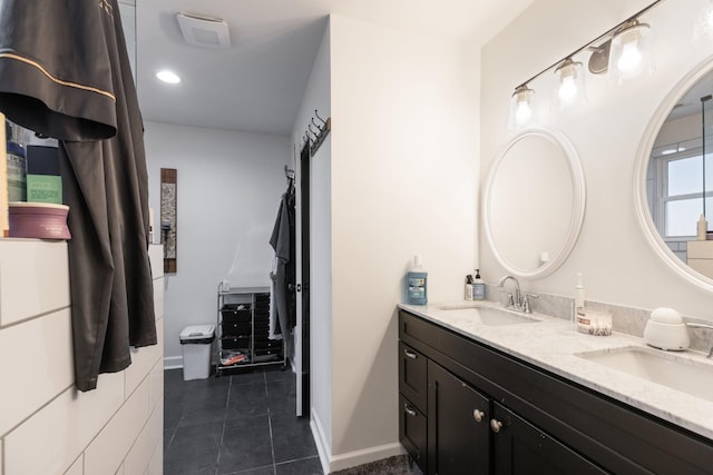 full bath featuring double vanity, a sink, baseboards, and tile patterned floors