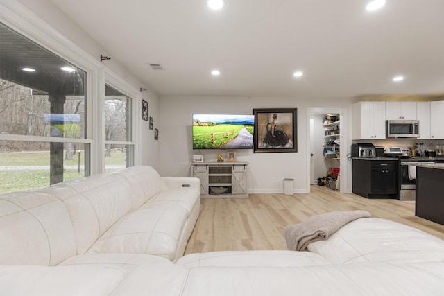 living room featuring light wood-style floors, baseboards, visible vents, and recessed lighting