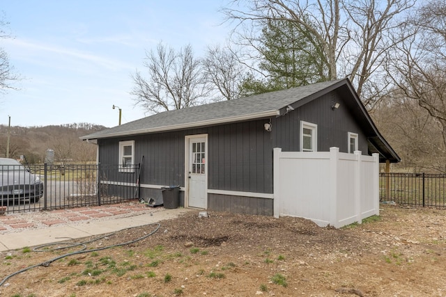 view of side of property featuring a shingled roof and fence