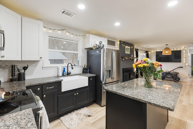 kitchen with range with electric stovetop, visible vents, white cabinets, a sink, and stainless steel fridge