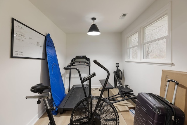 exercise area featuring light wood-style flooring and baseboards