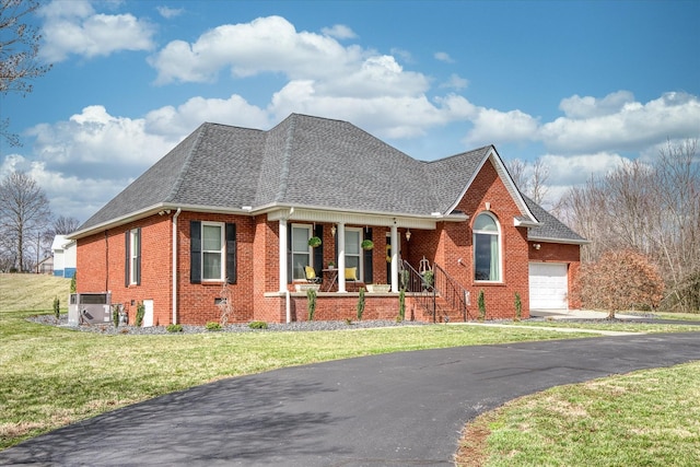 view of front of house featuring brick siding, a shingled roof, an attached garage, covered porch, and a front yard