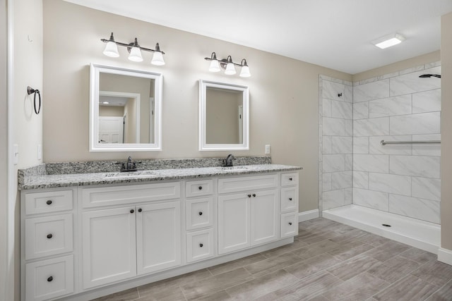 full bath with a sink, double vanity, and a tile shower