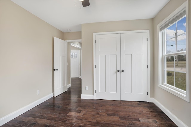 unfurnished bedroom with dark wood finished floors, a ceiling fan, baseboards, and a closet