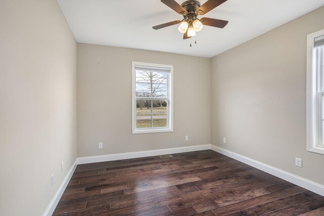 spare room featuring visible vents, ceiling fan, baseboards, and dark wood-style flooring