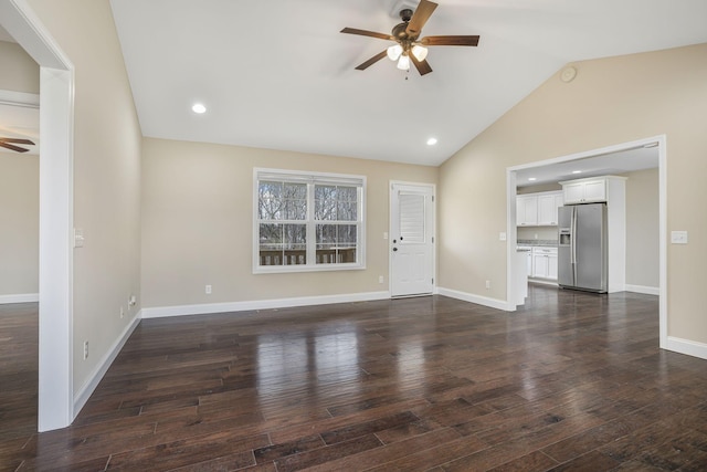 unfurnished living room with vaulted ceiling, a ceiling fan, dark wood-style flooring, and baseboards