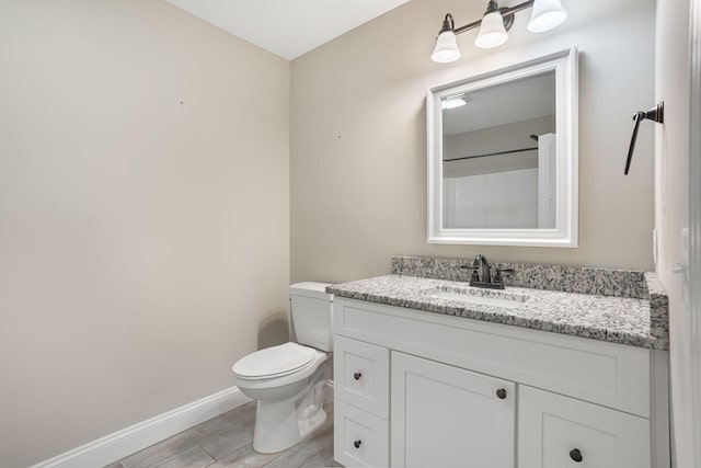 bathroom featuring toilet, vanity, baseboards, and wood finished floors