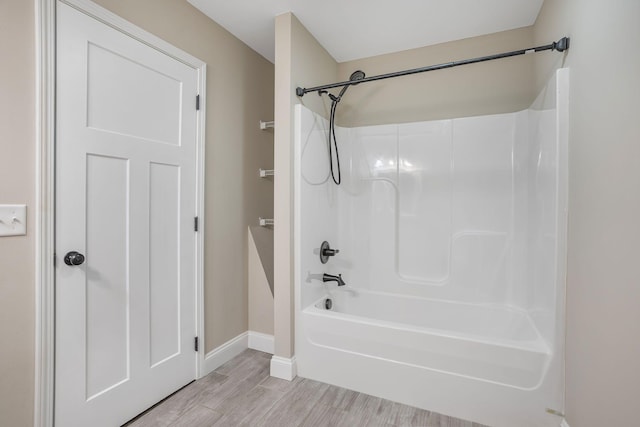 bathroom with wood finished floors, tub / shower combination, and baseboards