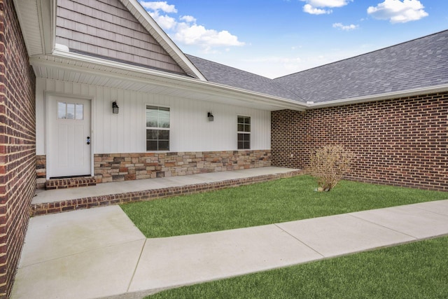 view of exterior entry featuring brick siding, stone siding, and a shingled roof