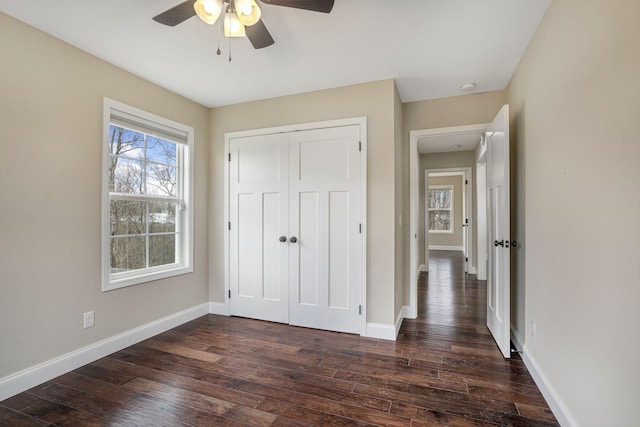 unfurnished bedroom featuring dark wood finished floors, ceiling fan, a closet, and baseboards