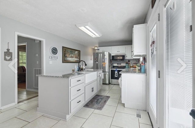 kitchen with visible vents, appliances with stainless steel finishes, a kitchen island with sink, white cabinetry, and a sink